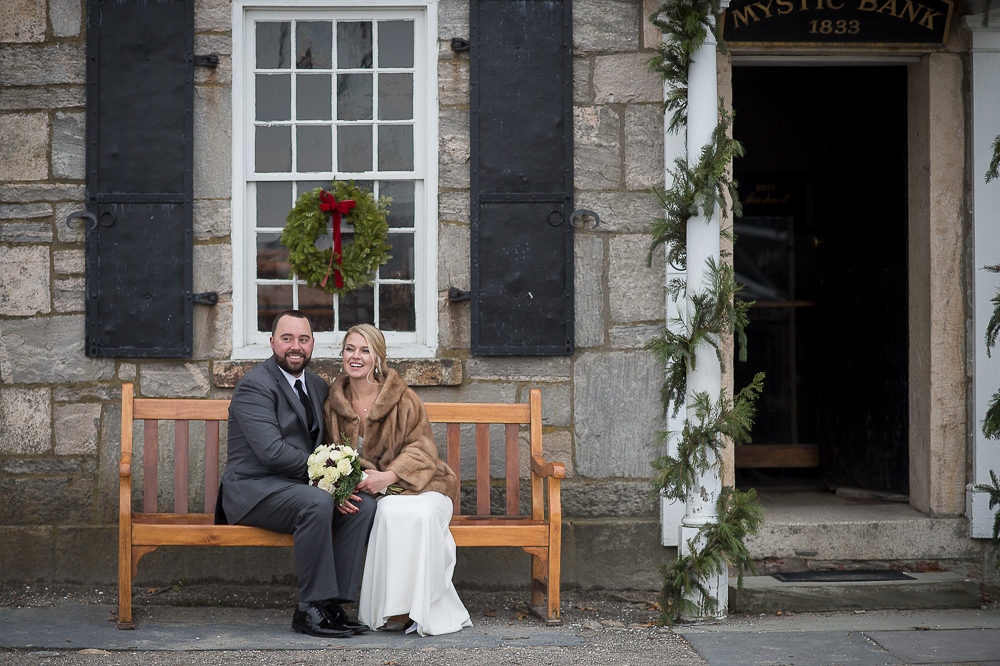 Bride in a fur coat and Groom sitting on a bench with Christmas Decorations